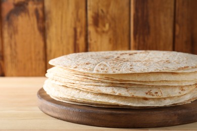 Many tasty homemade tortillas on wooden table, closeup