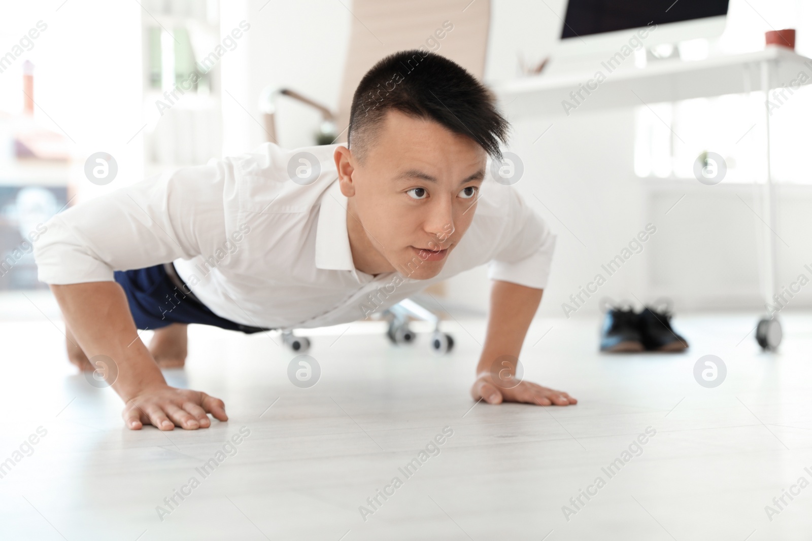 Photo of Young businessman doing exercises in office. Workplace fitness