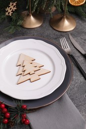 Festive place setting with beautiful dishware, cutlery and decorative tree for Christmas dinner on grey table