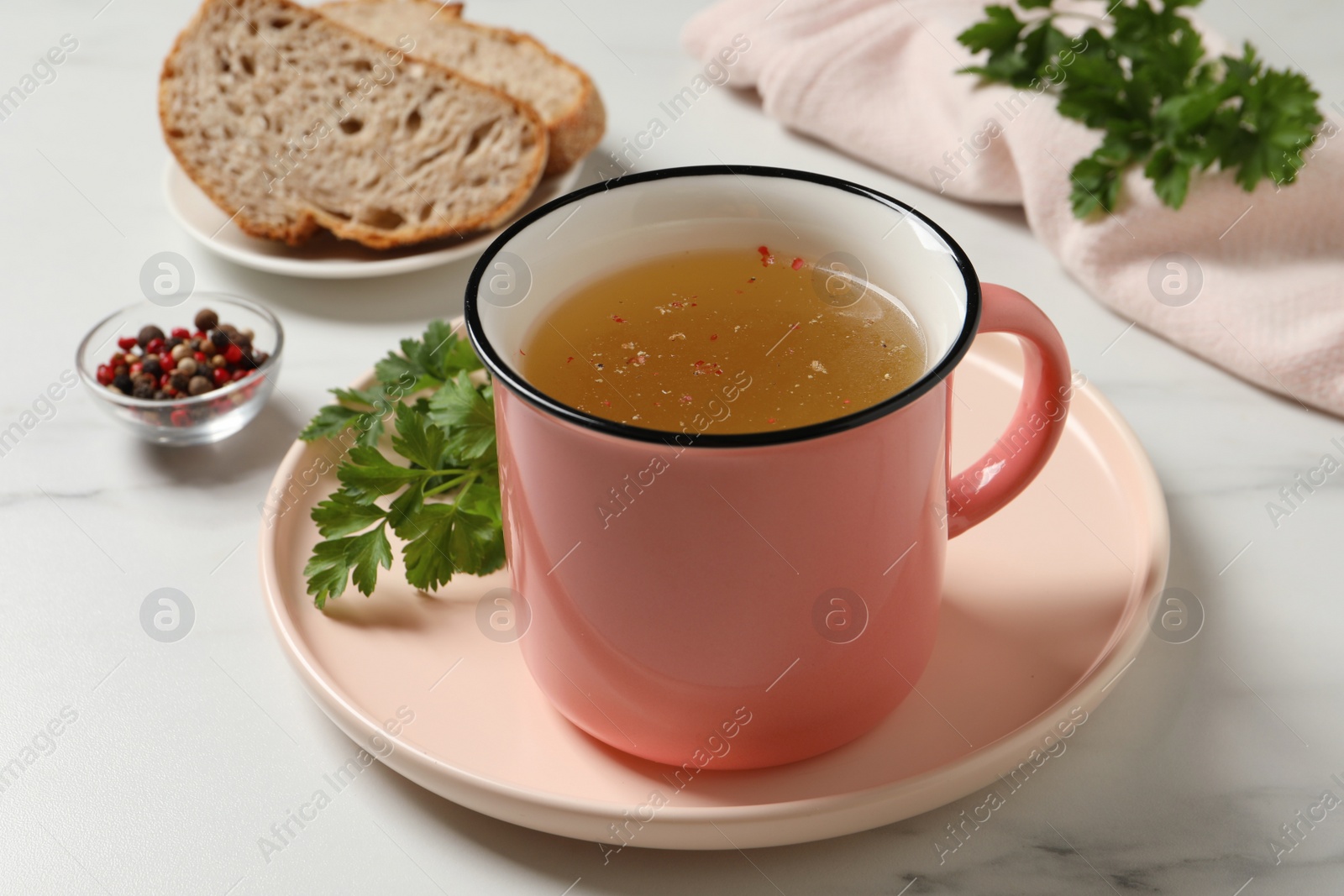 Photo of Hot delicious bouillon in cup on white marble table