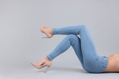 Photo of Woman wearing stylish jeans and high heels shoes on light gray background, closeup. Space for text