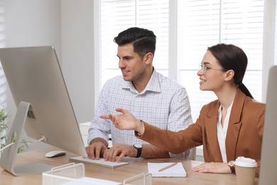 Businesswoman helping intern with work in office