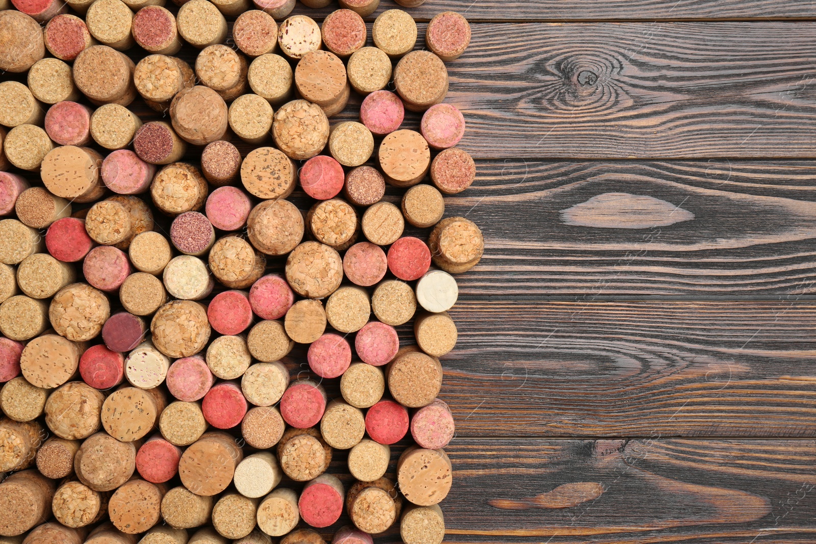 Photo of Many corks of wine bottles on wooden table, top view. Space for text