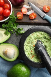 Mortar with delicious guacamole and ingredients on grey table, flat lay