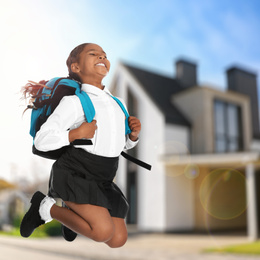 Image of Happy African American girl jumping near house. School holidays