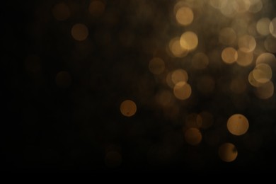 Photo of Blurred view of golden lights on black background. Bokeh effect