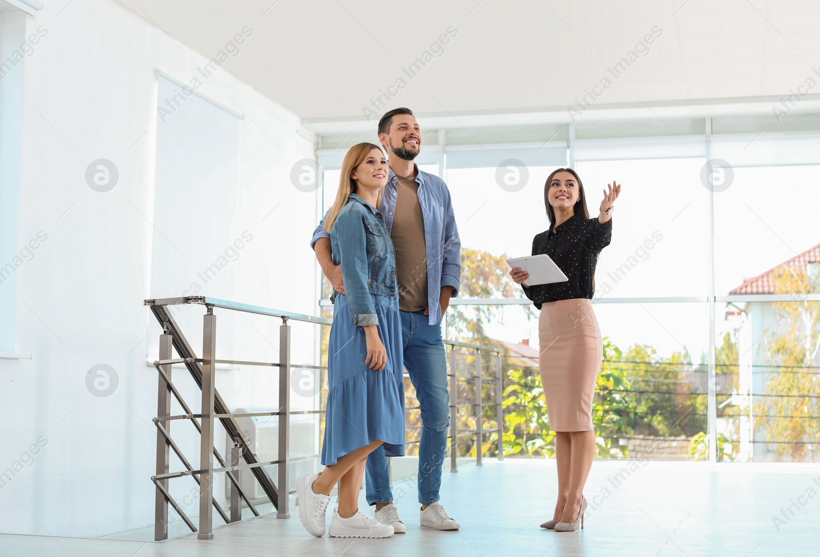 Photo of Female real estate agent showing new house to couple, indoors