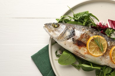 Photo of Baked fish with spinach and lemon on white wooden table, top view. Space for text