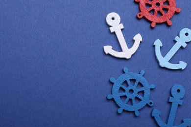 Photo of Anchor and ship wheel figures on blue background, flat lay. Space for text