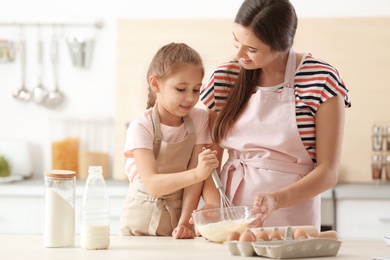 Mother and her daughter making dough at table in kitchen