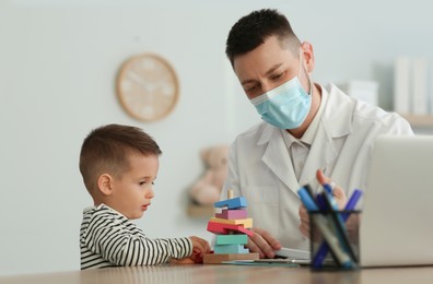 Pediatrician playing with little boy at hospital