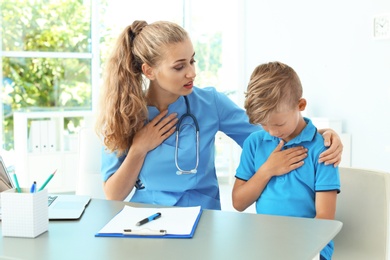 Photo of Female medical assistant consulting child in clinic