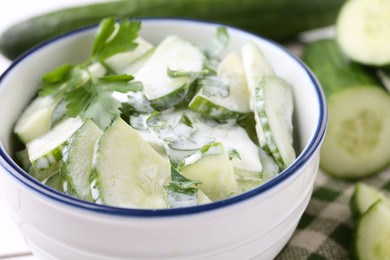 Delicious cucumber salad in bowl on table, closeup