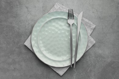 Photo of Clean plate, cutlery and napkin on grey table, top view