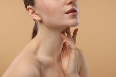 Photo of Woman touching her neck on beige background, closeup