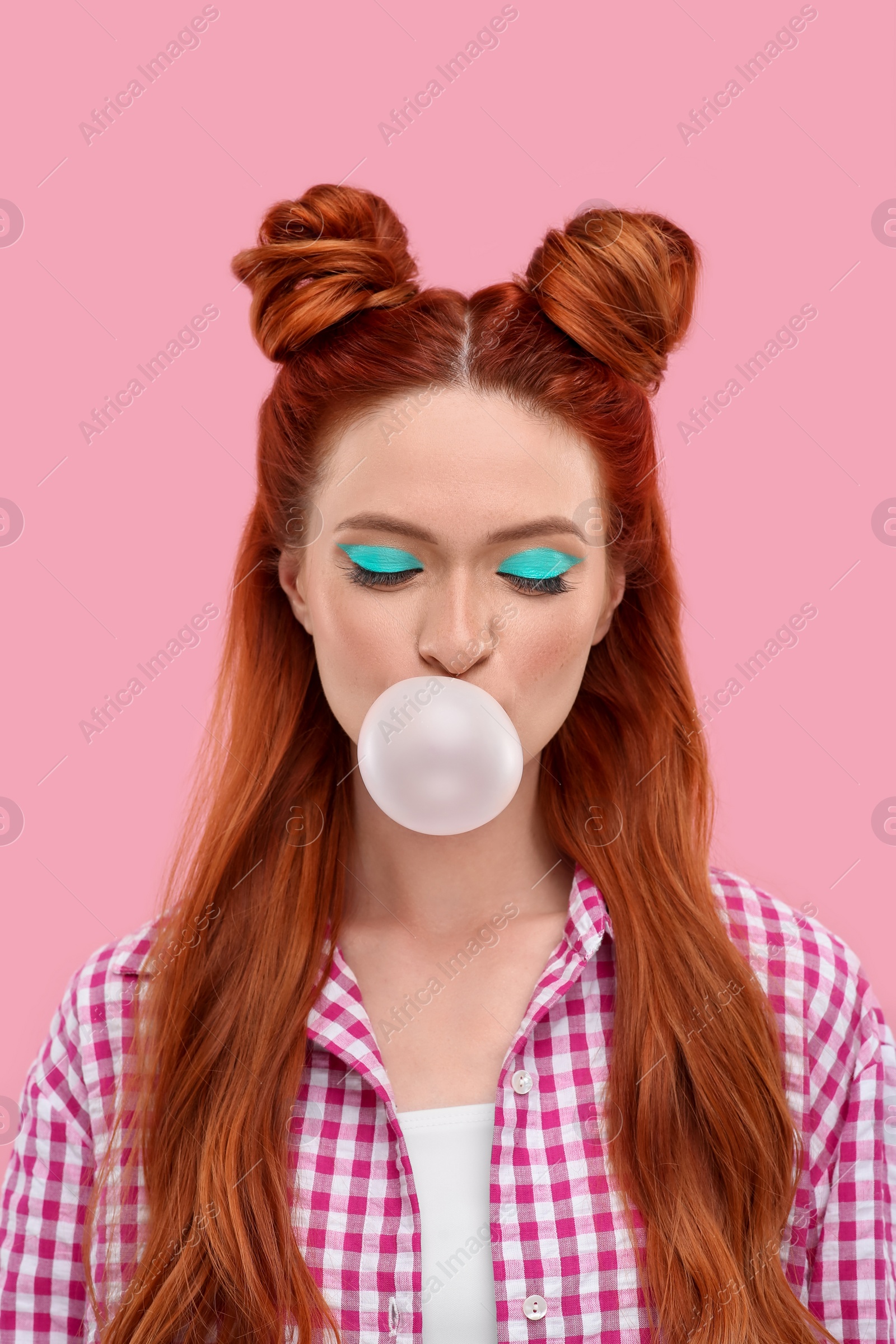 Photo of Beautiful woman with bright makeup blowing bubble gum on pink background