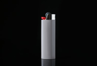Photo of Gray plastic cigarette lighter on black background, closeup