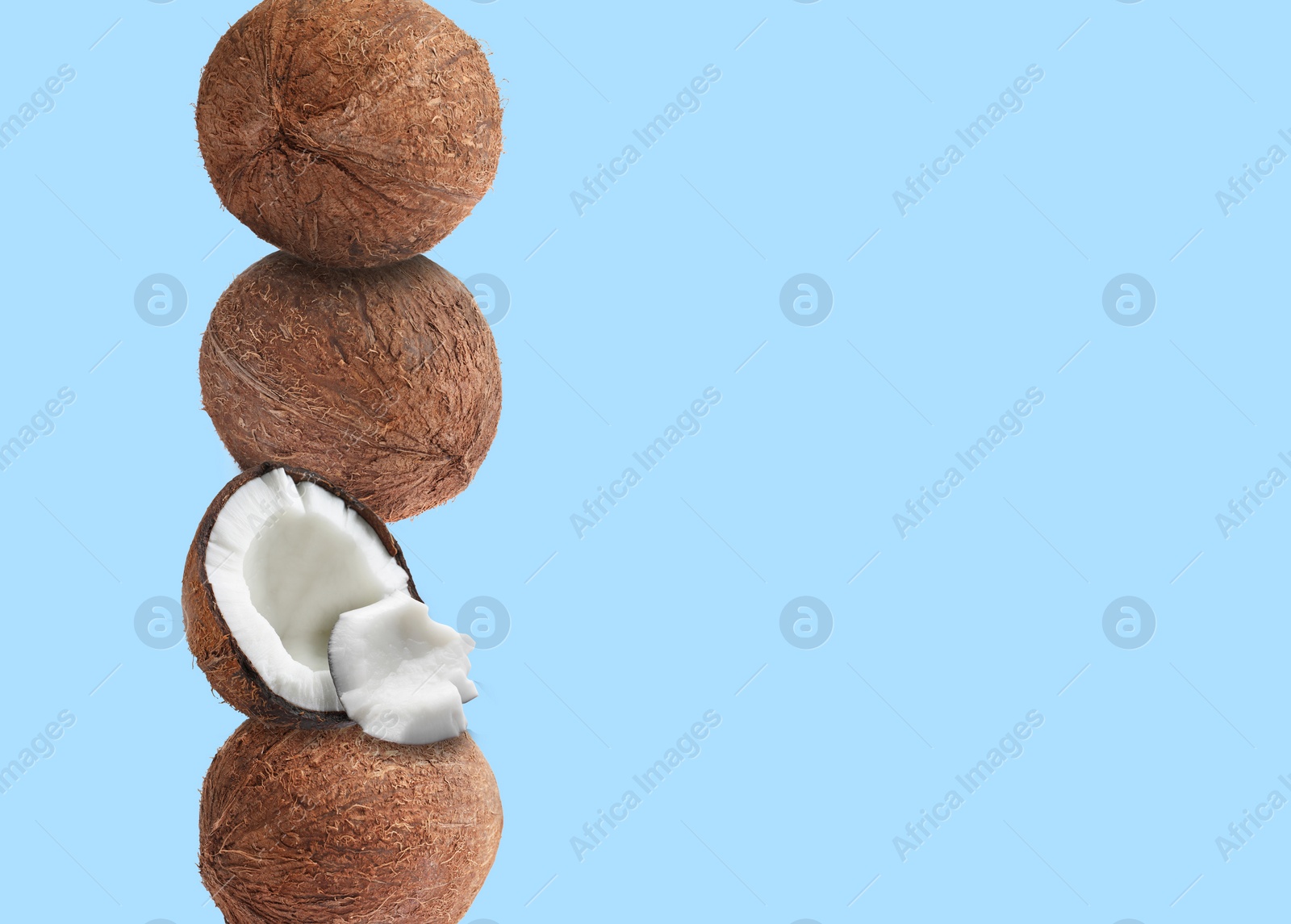 Image of Stack of fresh coconuts on pale light blue background. Space for text