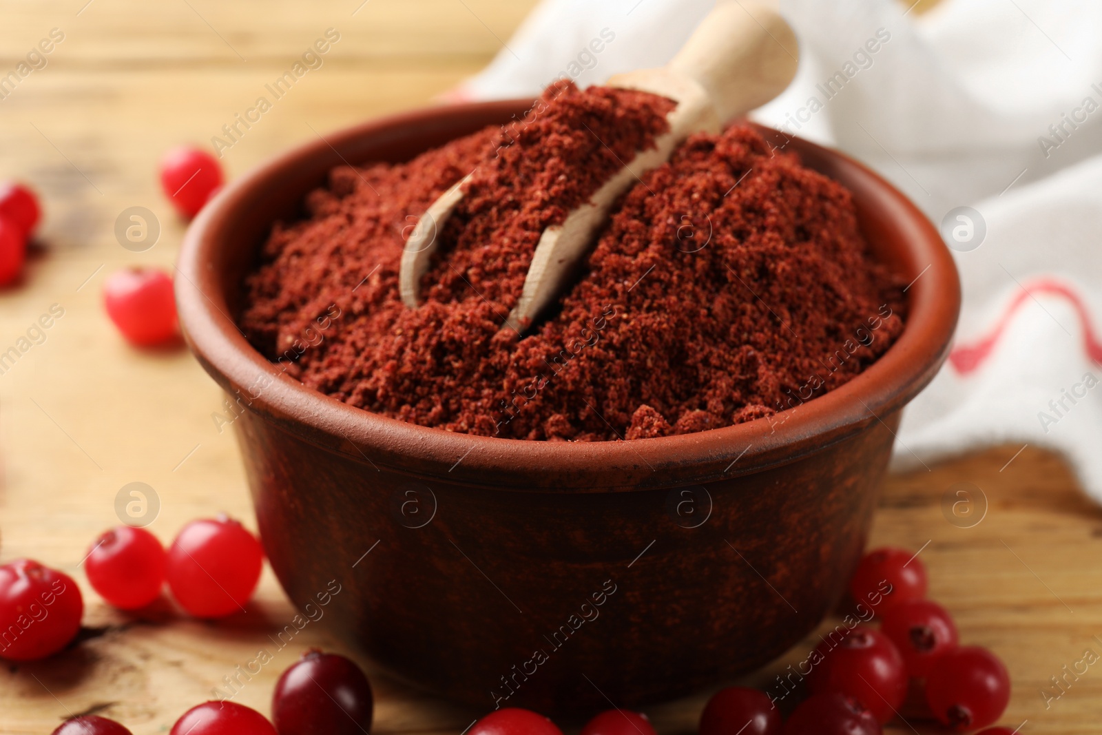 Photo of Cranberry powder in bowl, scoop and fresh berries on wooden table, closeup