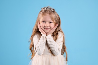 Photo of Cute girl in diadem on light blue background. Little princess