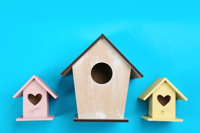 Photo of Beautiful bird houses on light blue background, flat lay