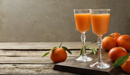 Delicious tangerine liqueur and fresh fruits on wooden table, space for text