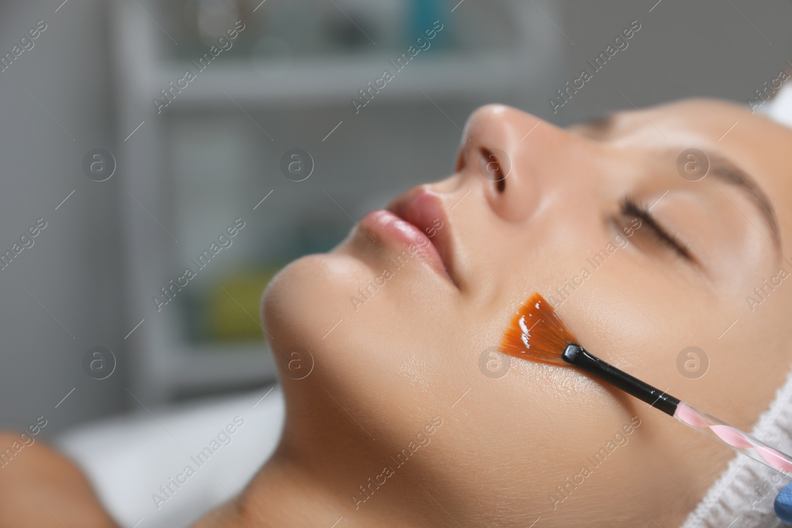 Photo of Young woman during face peeling procedure in salon, closeup