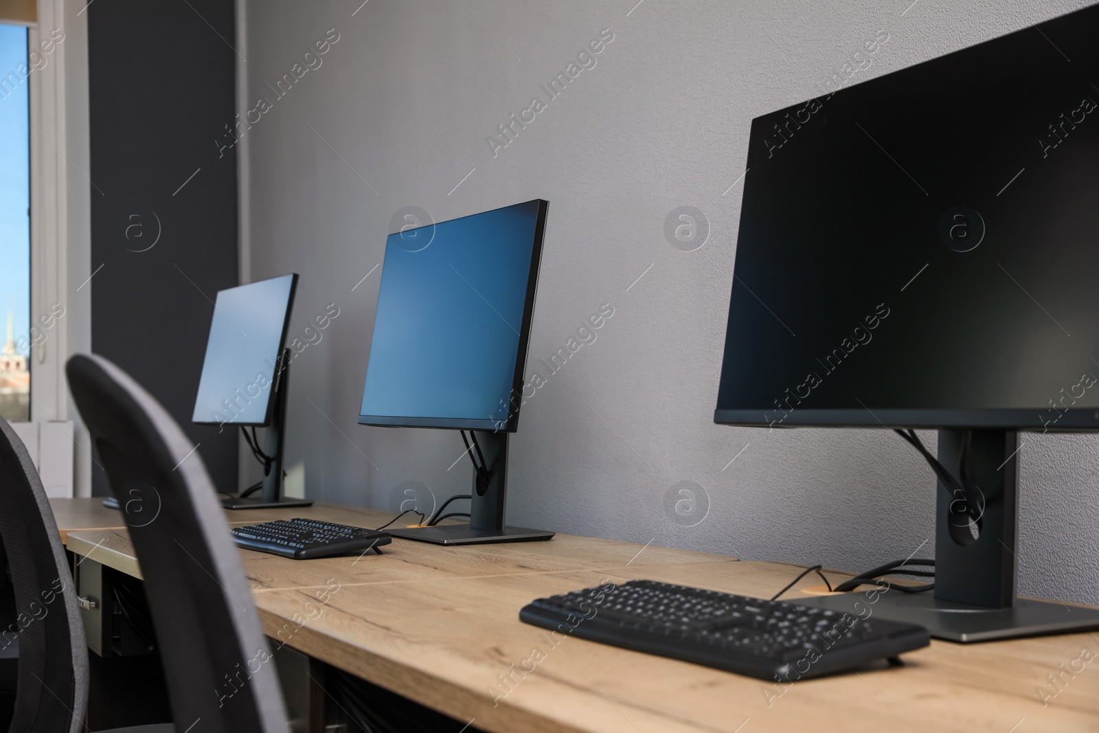 Photo of Open office interior. Modern workplaces with computers near light grey wall