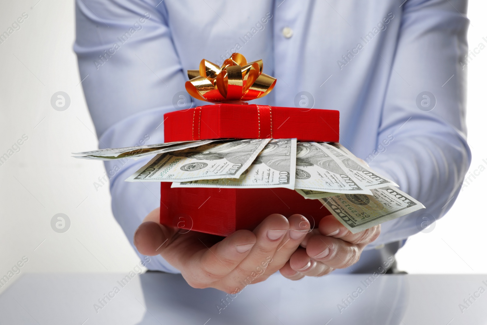 Photo of Man holding gift box with dollar banknotes on white background, closeup