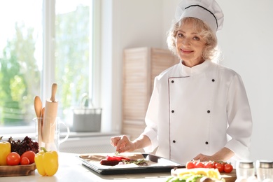 Professional female chef preparing meat in kitchen