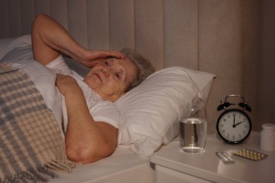 Elderly woman suffering from insomnia in bed at home
