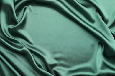 Crumpled green silk fabric as background, top view