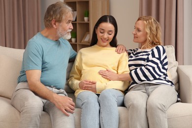 Photo of Happy pregnant woman spending time with her parents at home. Grandparents' reaction to future grandson