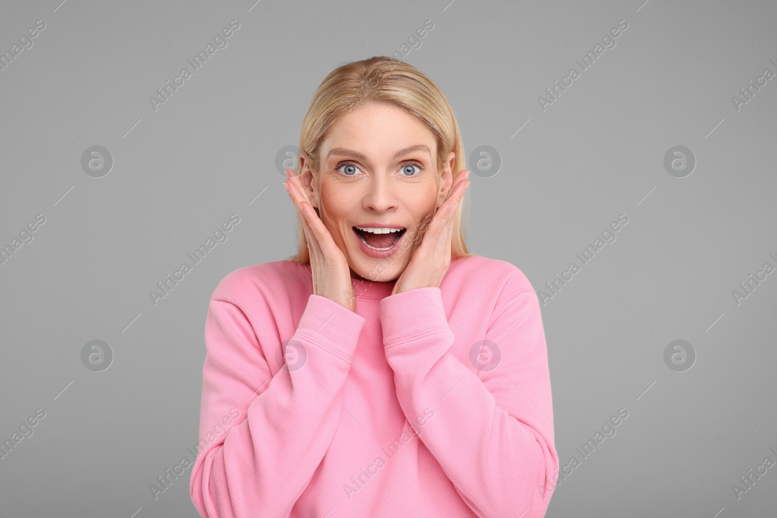 Photo of Portrait of happy surprised woman on grey background