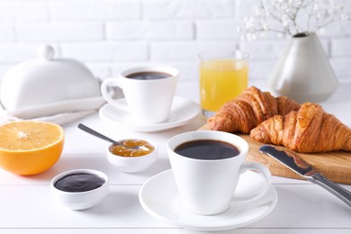 Cup of coffee, jam and croissants on white wooden table. Tasty breakfast