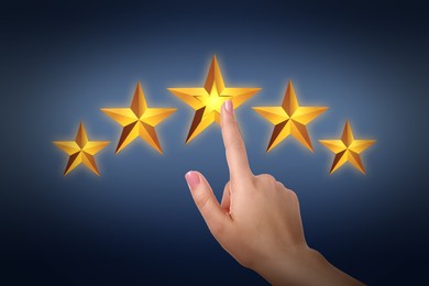 Image of Quality rating. Woman pointing at virtual stars on dark background, closeup