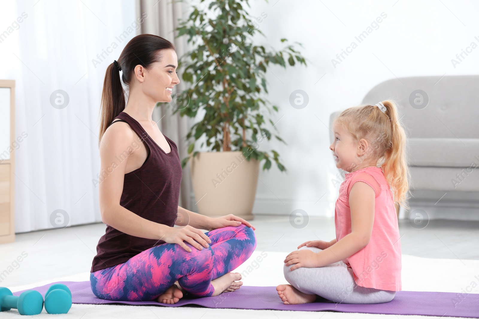 Photo of Sportive woman doing fitness exercises with daughter at home