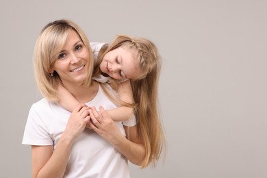 Photo of Family portrait of happy mother and daughter on grey background. Space for text