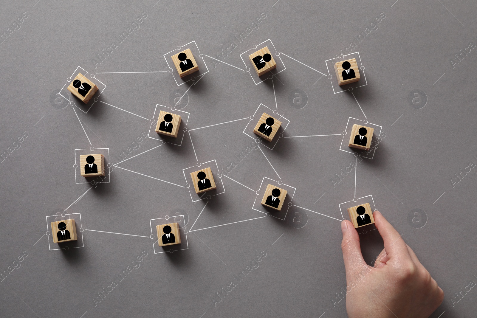 Image of Teamwork. Woman arranging wooden cubes with human icons linked together symbolizing cooperation at grey table, top view