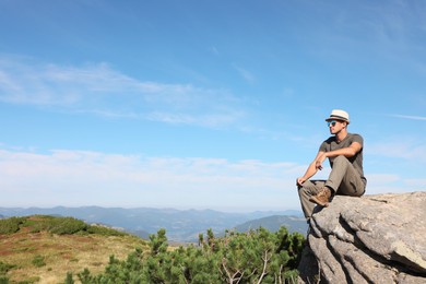 Photo of Man enjoying picturesque view on cliff in mountains. Space for text