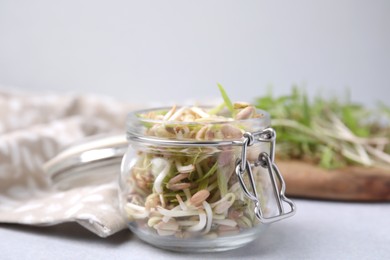 Photo of Mung bean sprouts in glass jar on white table, closeup