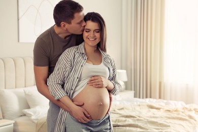 Young pregnant woman with her husband in bedroom