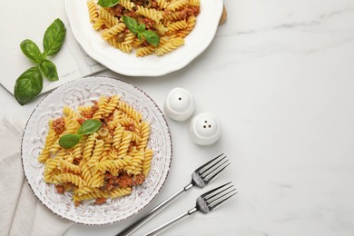 Delicious pasta with minced meat and basil served on white marble table, flat lay. Space for text