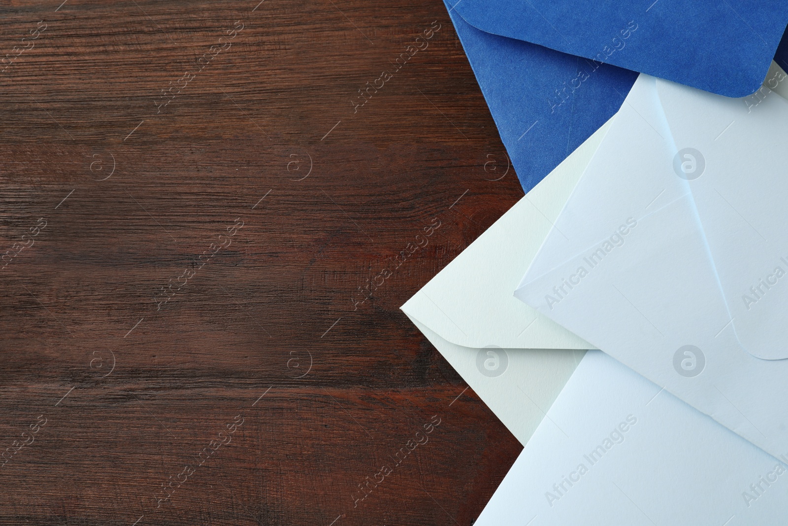 Photo of Colorful paper envelopes on wooden table, top view. Space for text