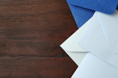Colorful paper envelopes on wooden table, top view. Space for text
