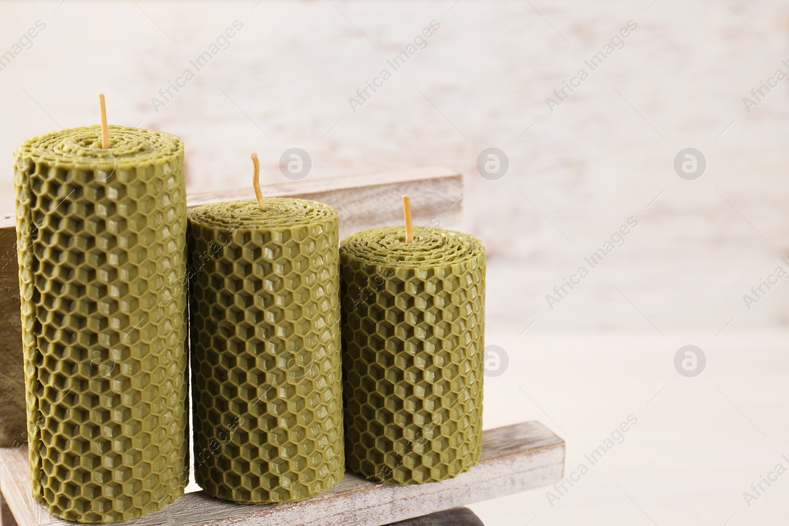 Photo of Stylish elegant beeswax candles on white wooden table, space for text