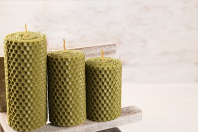 Stylish elegant beeswax candles on white wooden table, space for text