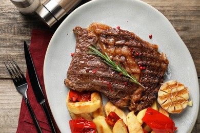 Photo of Delicious grilled beef steak and vegetables served on wooden table, top view