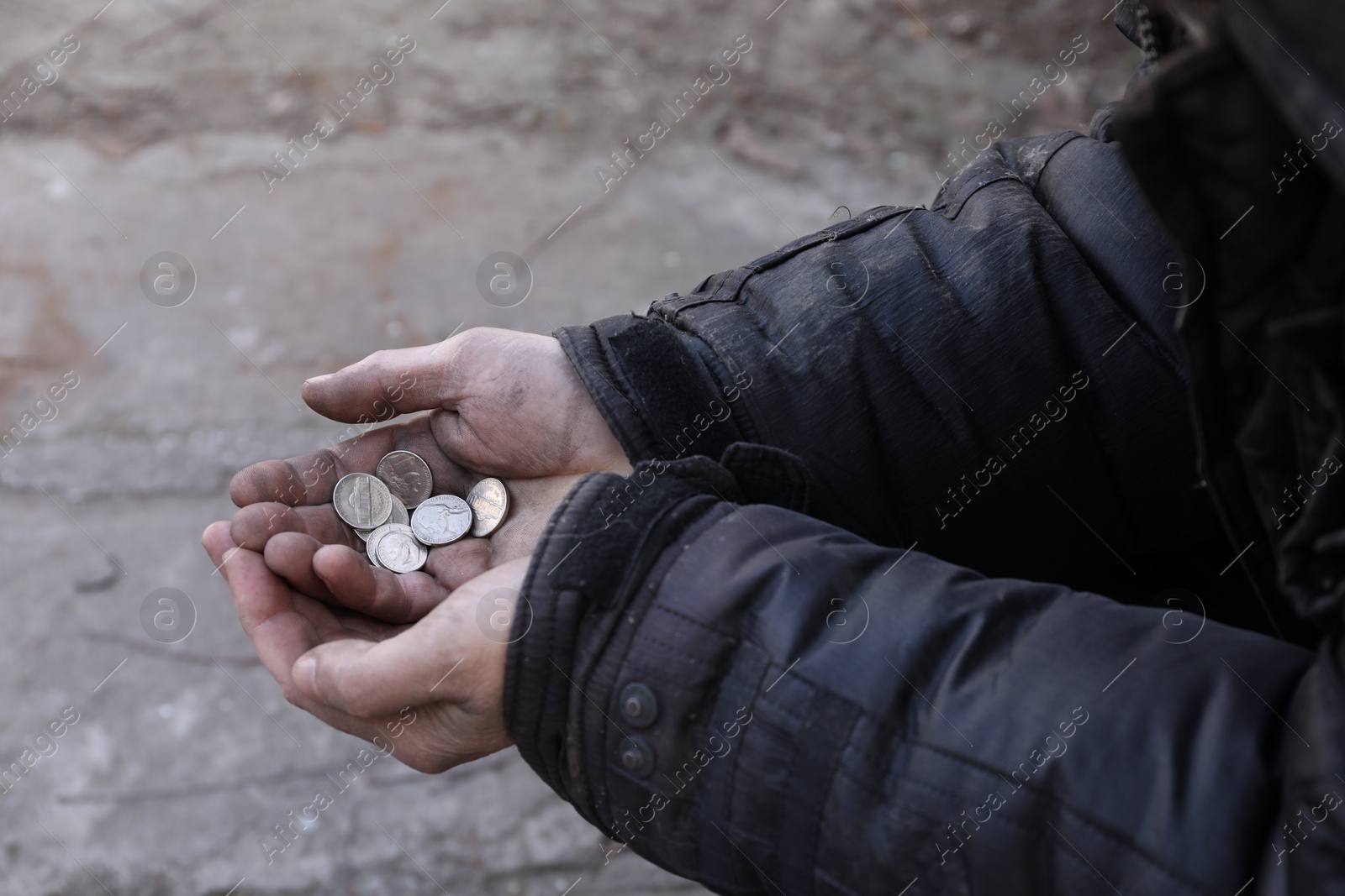 Photo of Poor homeless man holding coins outdoors, closeup