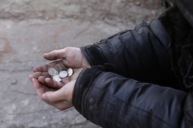 Poor homeless man holding coins outdoors, closeup